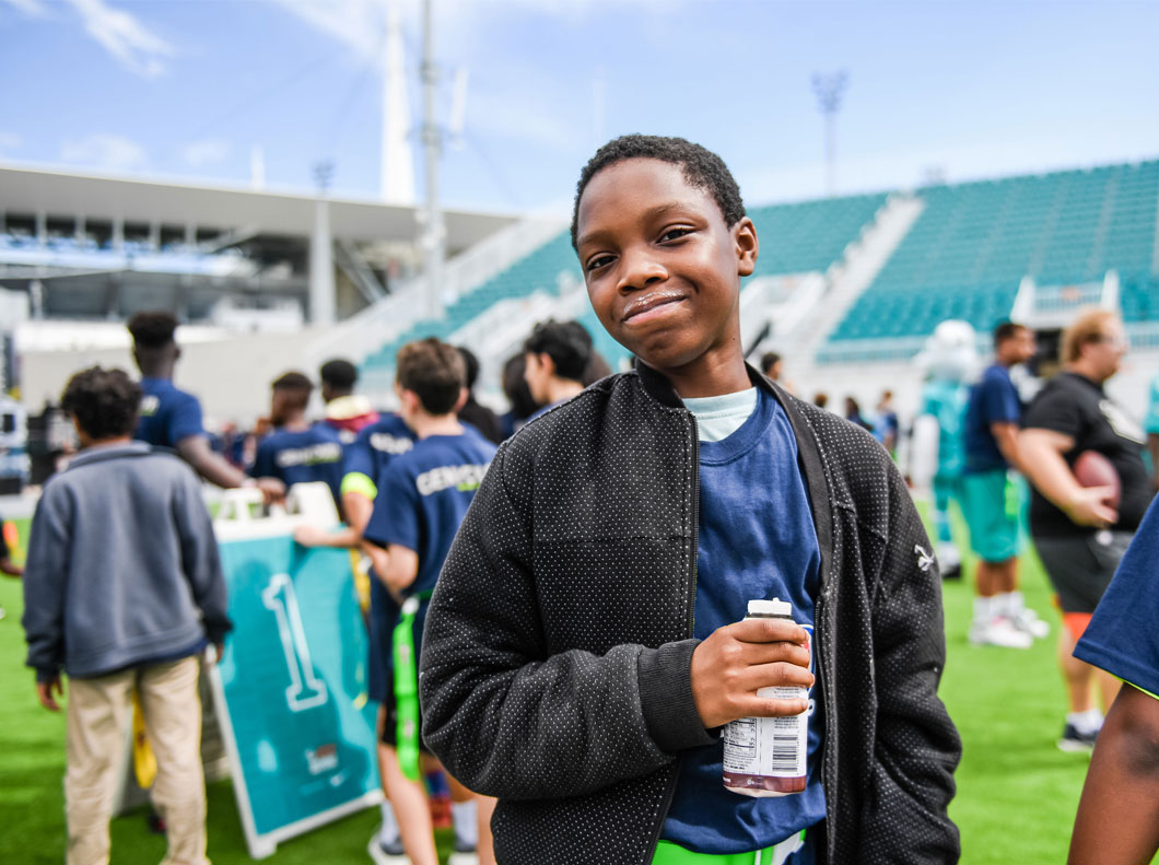 Kid holding a milk bottle on a football field