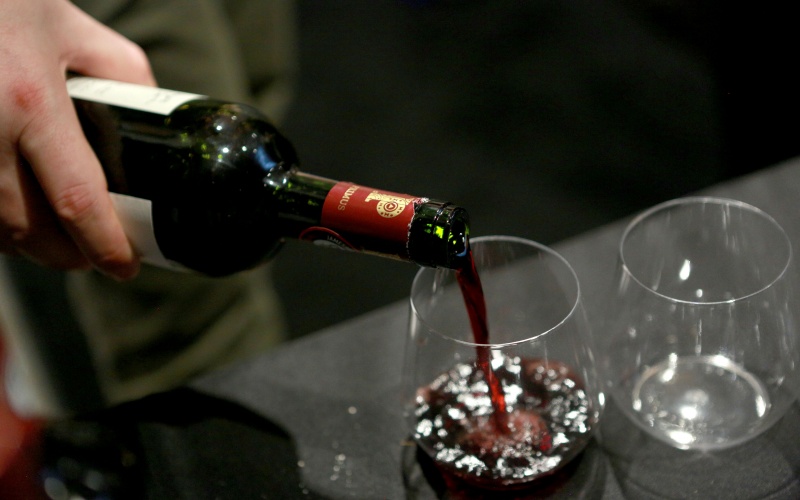 a hand pouring wine into a wine glass