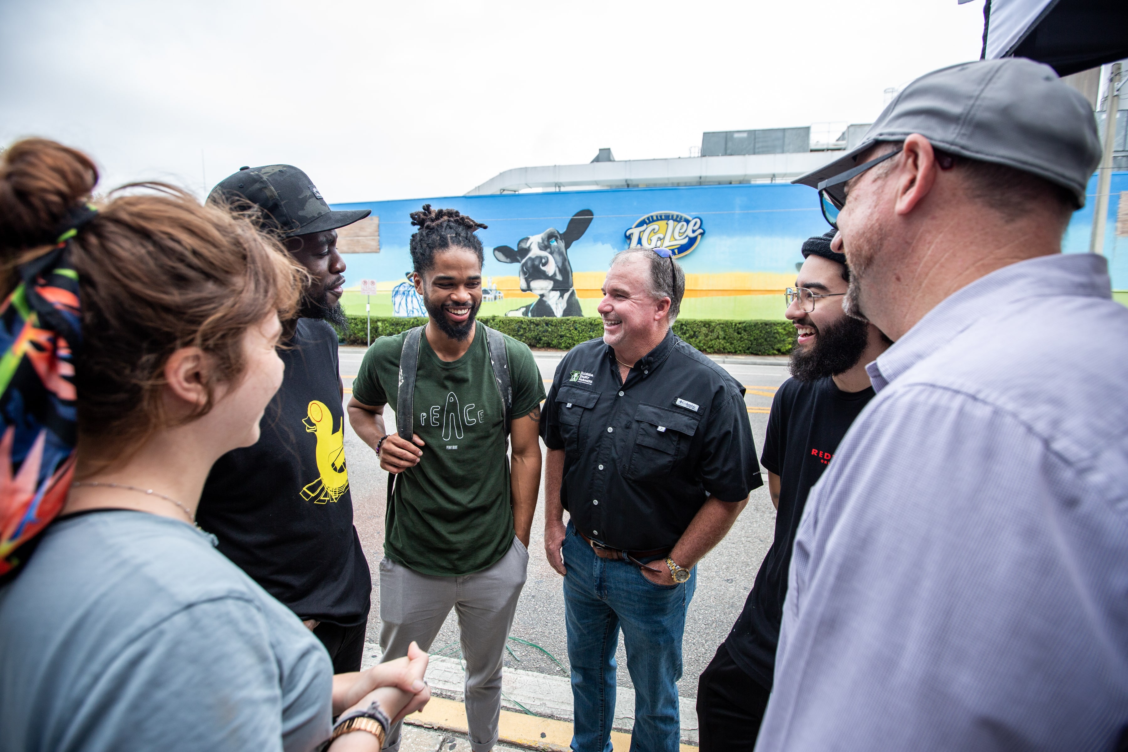 artists, dairy farmers, and more have a milk toast in front of mural